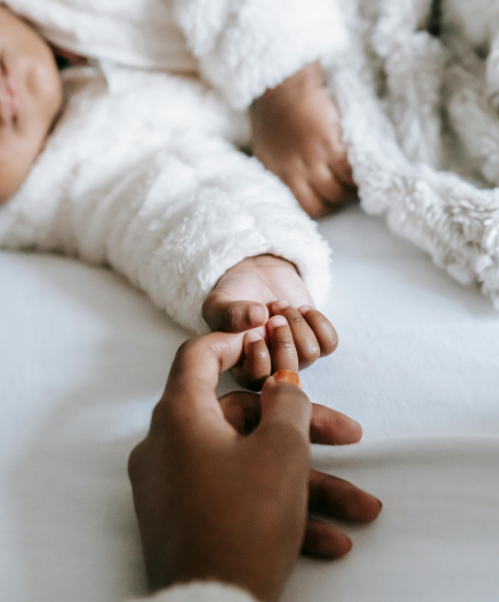 Baby laying down and holding mothers finger