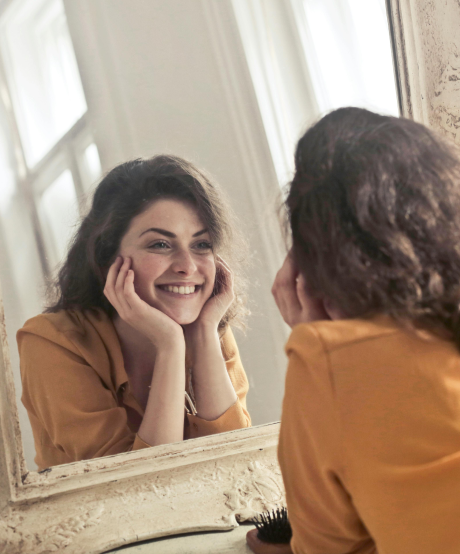 Confident women looking and smiling at herself in the mirror Confident women looking and smiling at herself in the mirror