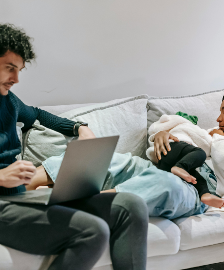 New parents sitting on couch while mother feeds baby New parents sitting on couch while mother feeds baby