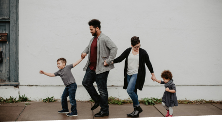 Happy family holding hands and walking down the sidewalk